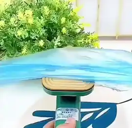 La mini plancha a vapor en la mano, con su suela dorada